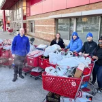 Five members of the Blue Horizon Energy staff pose with eleven shopping carts of toys they purchased for the Tots for Tots charity.